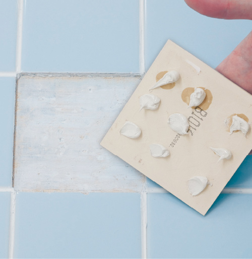 3.新しいタイルの裏側に浴室タイル用接着剤を点塗りし、押さえ付けながら貼ります。目地の間隔が均等になるように注意。