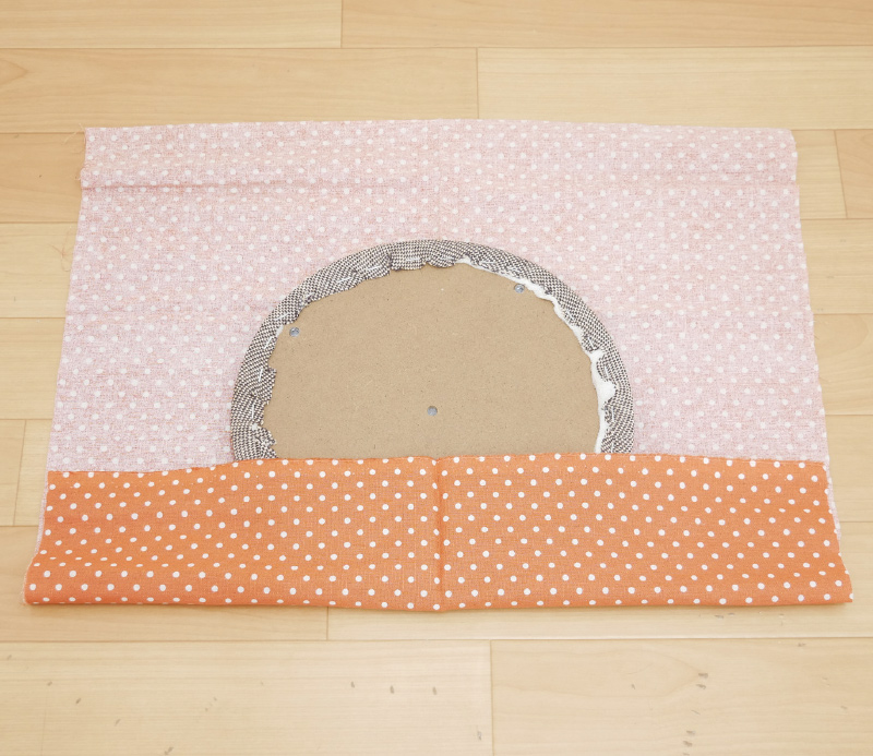 4.布の端を座面側に折り返して、古い張り地がすっぽりと隠れるように、座面の位置を調節します。