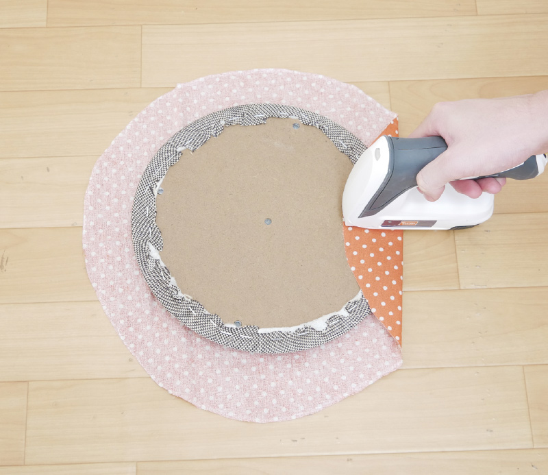 6.椅子の背もたれ部分（先に書き込んだ矢印方向）から張り地を止めていきます。座面のカーブに沿って少しずつひだを寄せながら、タッカーで2～3カ所止めます。