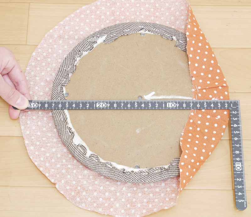 8.次に書き込んだ矢印を支点にして定規をあて、最も距離の遠い対角線側の張り地を止めます。背もたれ部分と同じくひだを寄せながら2～3カ所止めます。